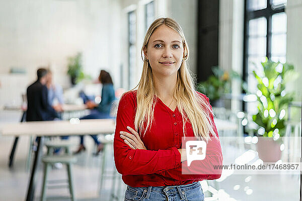 Smiling blond businesswoman with arms crossed in office