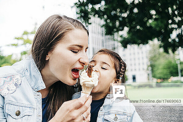 Mother and daughter sharing ice cream at public park
