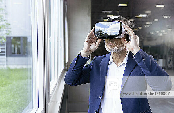 Businessman wearing virtual reality simulator by window in factory
