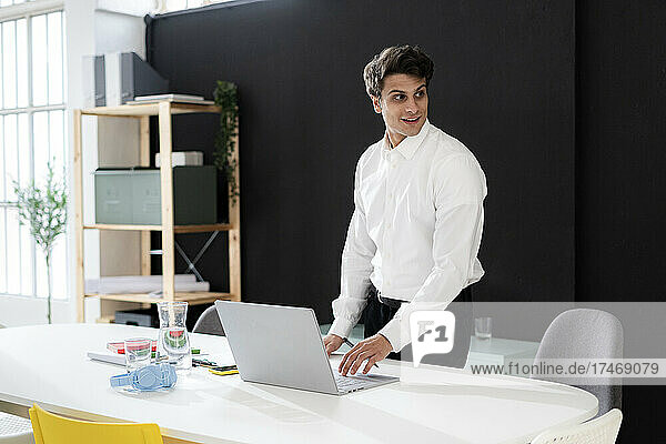 Junger Geschäftsmann arbeitet im Büro am Laptop