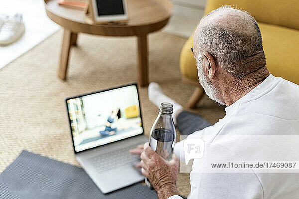 Man watching online yoga tutorial on laptop at home