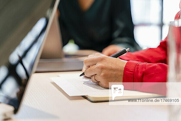 Businesswoman writing on paper at office desk