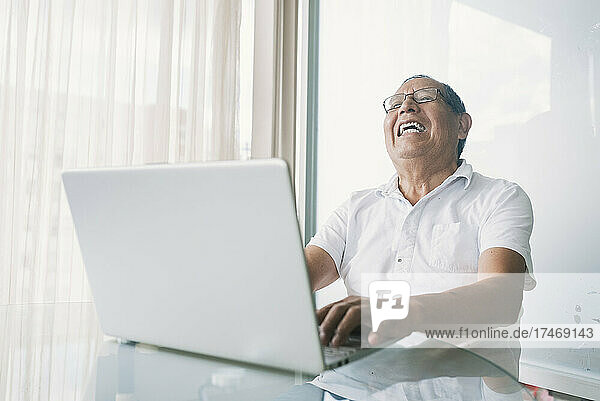 Happy businessman with laptop working at home office