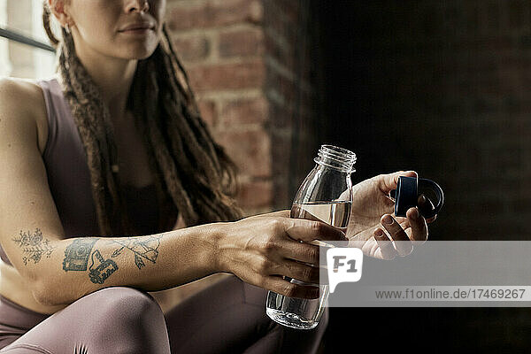 Thirsty athlete holding water bottle in yoga studio