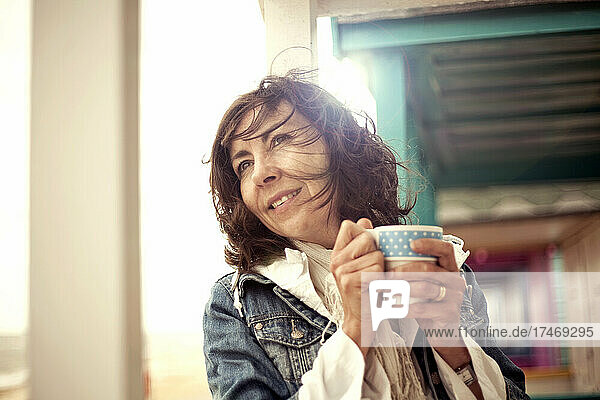 Smiling woman holding coffee mug in hut