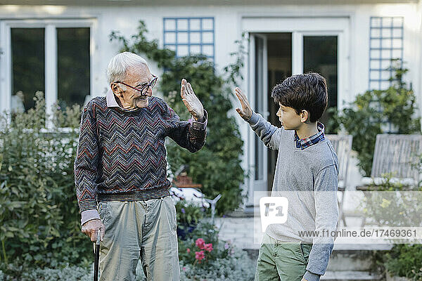 Großvater gibt seinem Enkel im Hinterhof ein High-Five