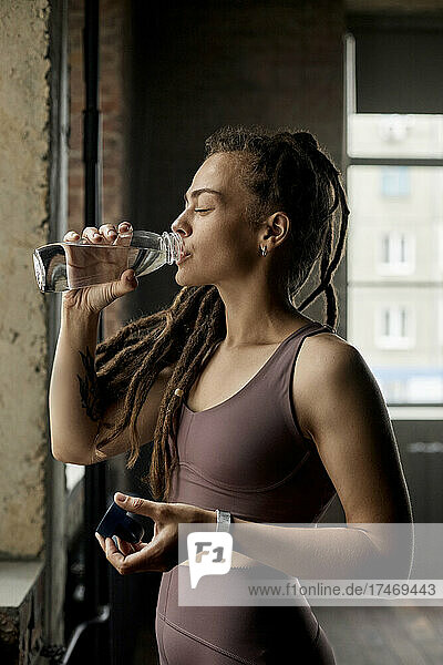 Sportswoman drinking water in fitness studio