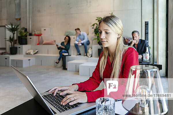 Blond businesswoman using laptop at desk