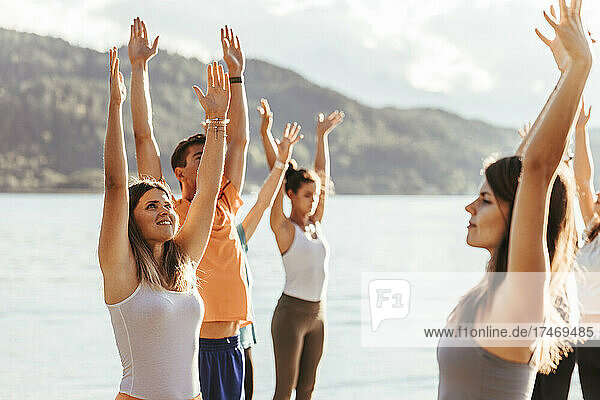 Female yoga instructor with men and women doing yoga during sunny day