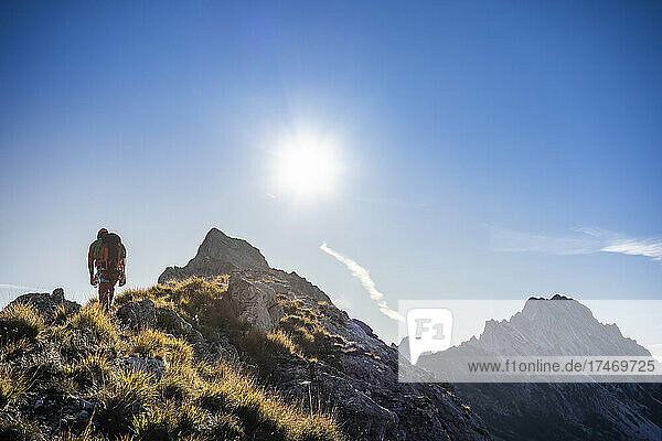 Männlicher Bergsteiger wandert an einem sonnigen Tag am Bergrücken