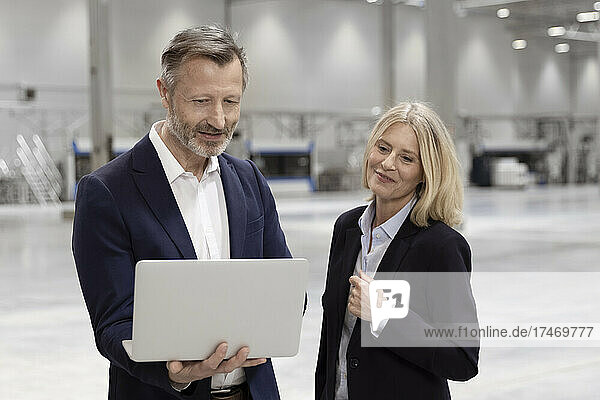 Mature businessman discussing over laptop with female colleague in industry