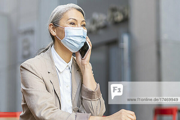 Woman wearing protective face mask talking on smart phone