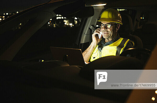 Engineer with laptop talking on smart phone in car