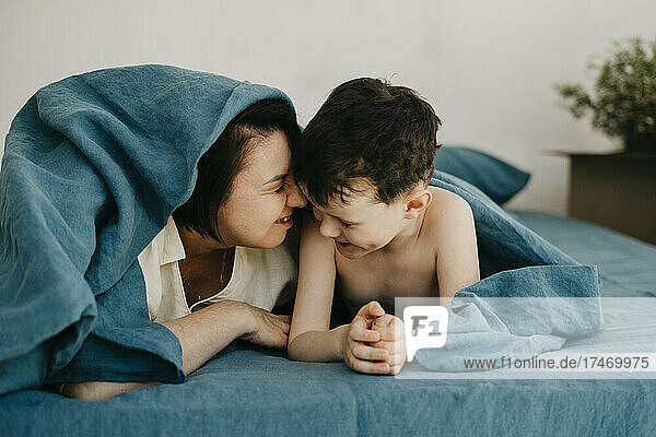 Playful mother and son lying on bed in bedroom