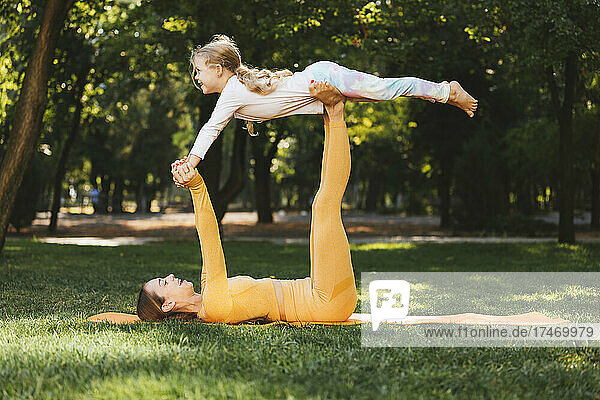 Happy mother lifting daughter on legs in park
