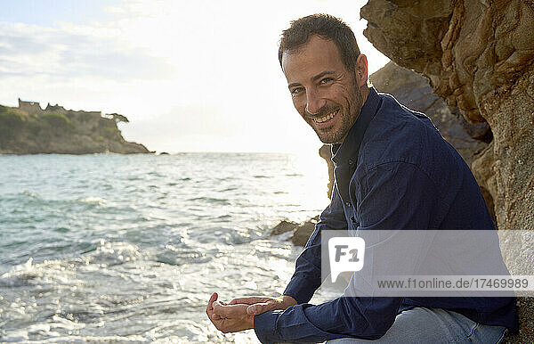 Smiling man enjoying by sea at sunset