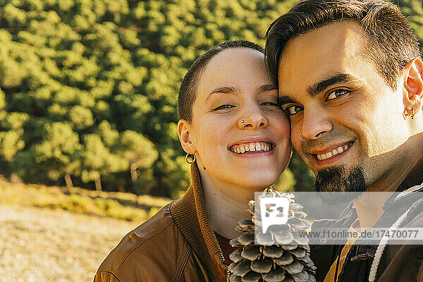 Smiling couple with pine cone on mountain