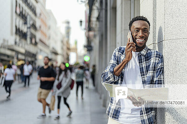 Man with map talking on smart phone in city