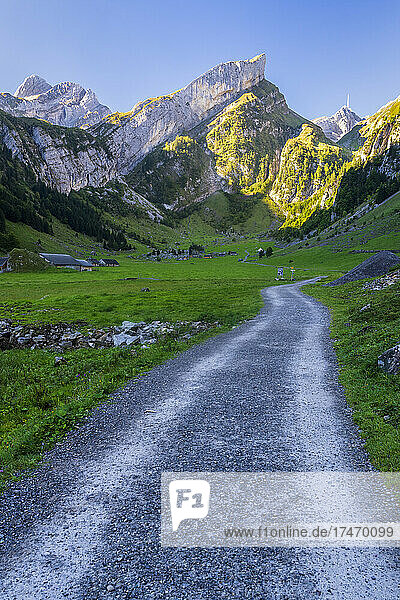 Empty dirt road stretching through valley in Alpstein range at dawn