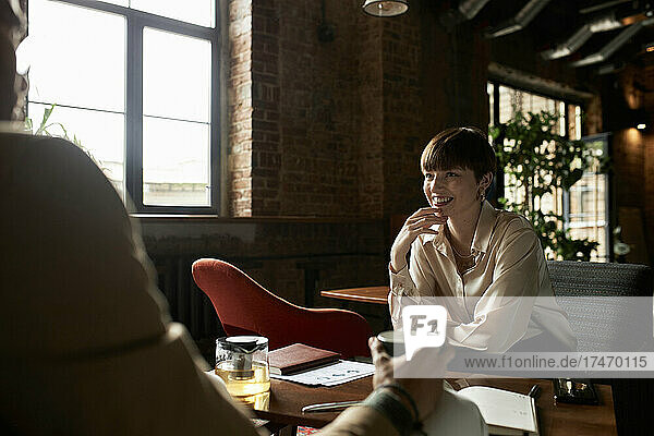 Smiling teenage girl looking at boyfriend in cafe