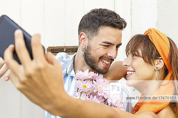 Girlfriend taking selfie with boyfriend through smart phone