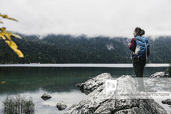 Female backpacker standing on rock at lakeside