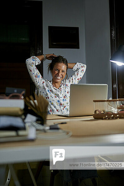 Businesswoman tying hair while sitting at desk in office during night