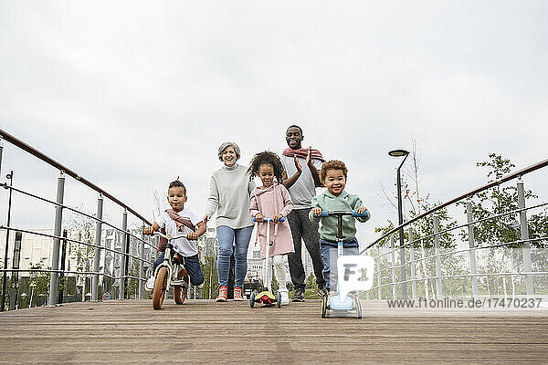 Kinder spielen mit Tretroller und Fahrrad auf der Brücke