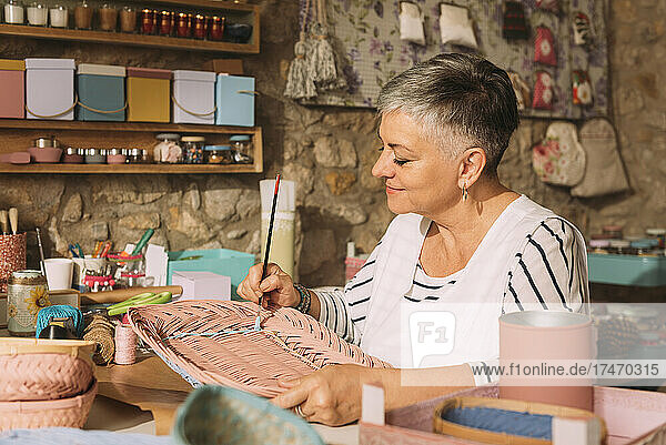 Female artist painting wicker in workshop