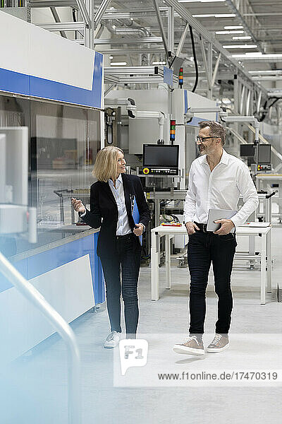 Smiling male and female professionals discussing in factory