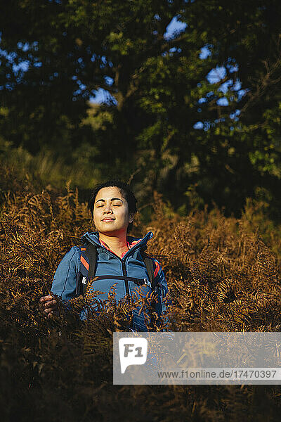 Woman with eyes closed amidst plants in forest
