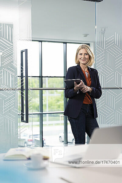 Smiling businesswoman holding digital tablet in office