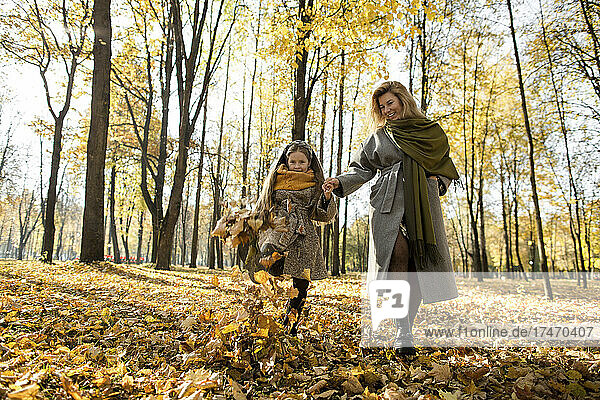 Playful girl and mother having fun in autumn park
