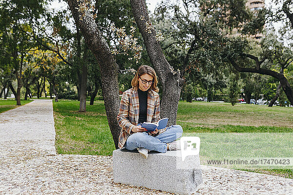 Freelancer reading book on bench at park