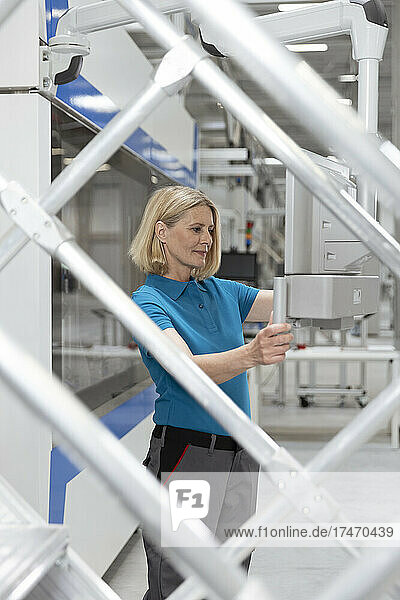 Woman examining machinery seen through railing at factory