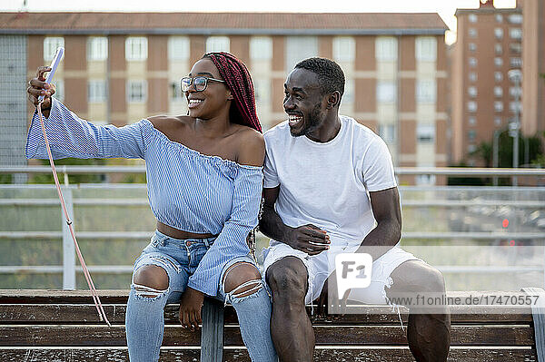 Glückliches Paar macht ein Selfie mit dem Smartphone auf der Bank