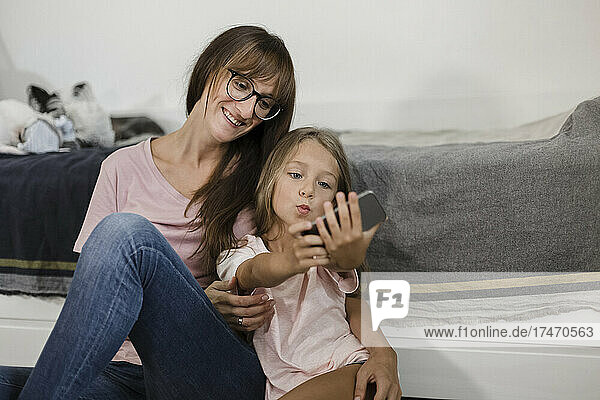 Girl taking selfie with woman through mobile phone at home