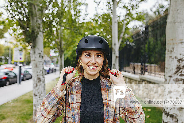 Smiling freelancer wearing helmet outside park