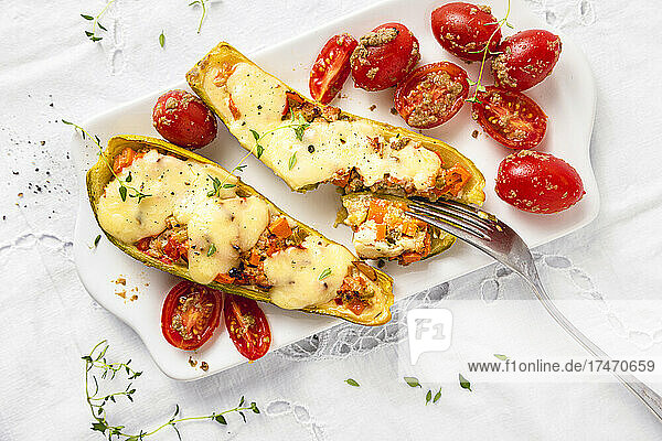 Garnished stuffed zucchini with cherry tomatoes and fork in plate