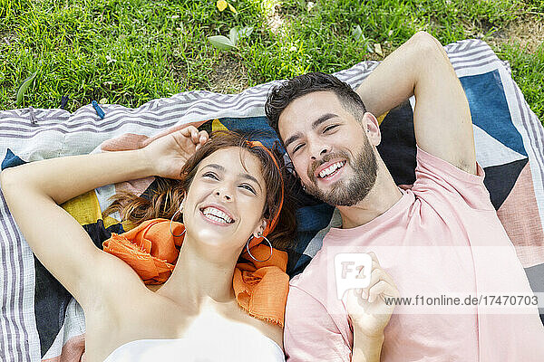 Smiling young couple lying on picnic blanket