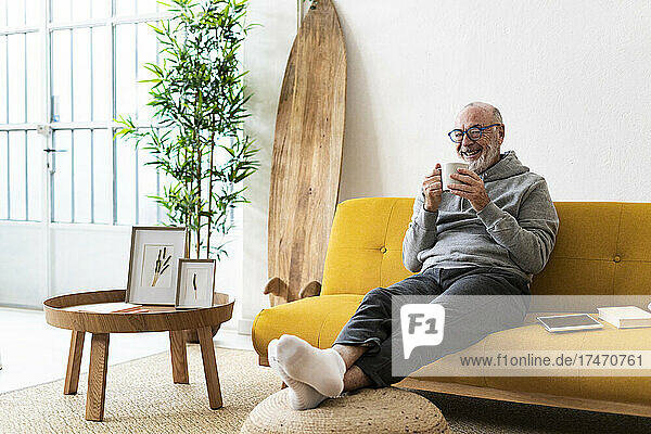 Smiling senior man drinking coffee on sofa