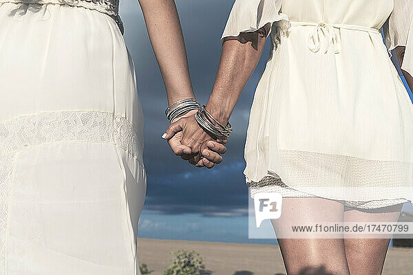 Lesbian couple holding hands on sunny day