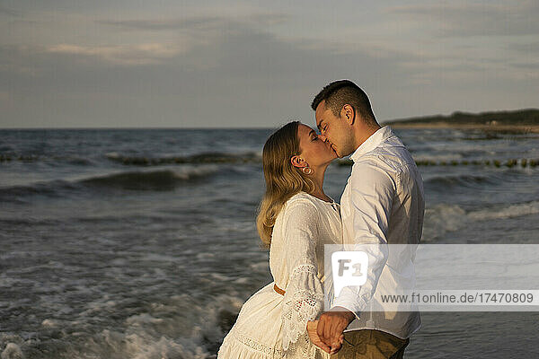 Young couple kissing on mouth at beach by sea