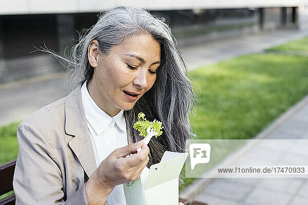 Mature woman eating salad from food box