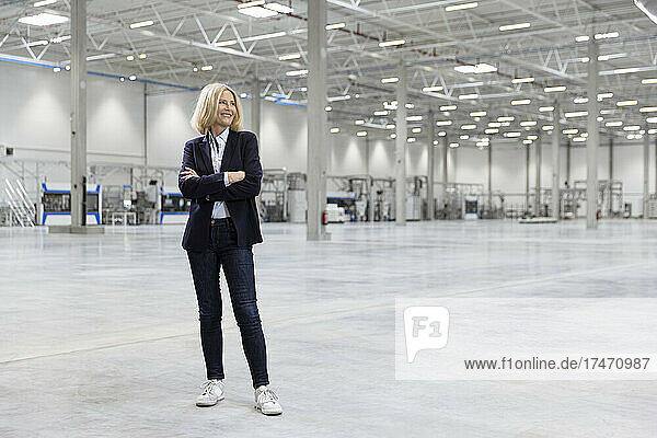 Happy female professional standing with arms crossed in industry