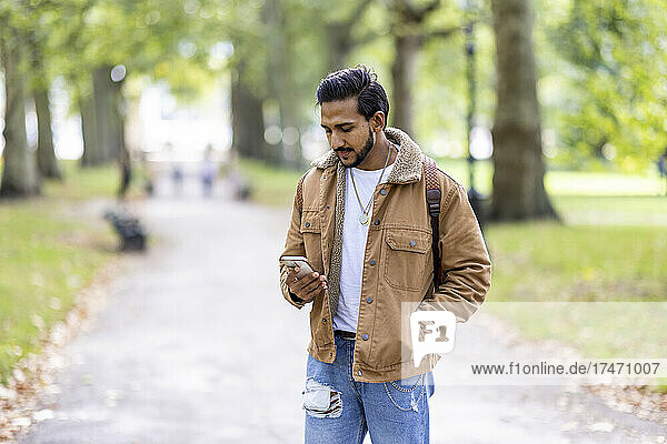 Junger Mann benutzt Smartphone im Park