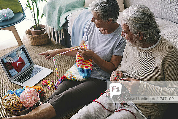 Woman watching knitting tutorial with man at home