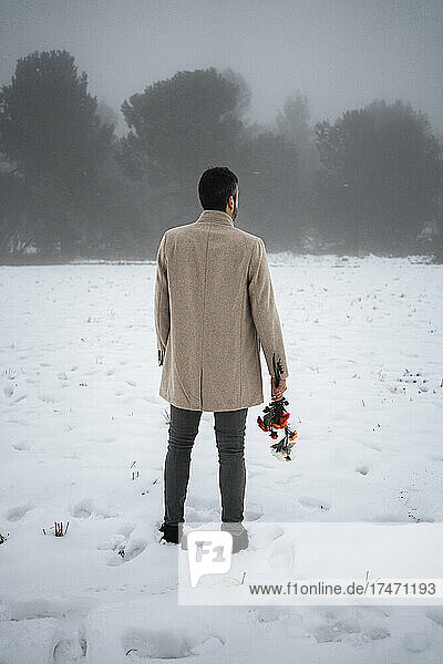 Man with flowers standing on snow during winter