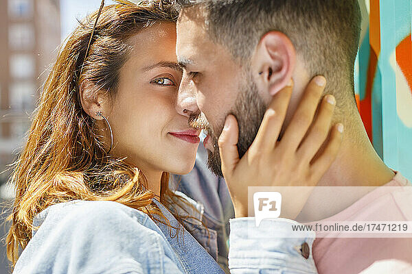 Lächelnde Freundin macht an sonnigen Tagen Romanze mit ihrem Freund