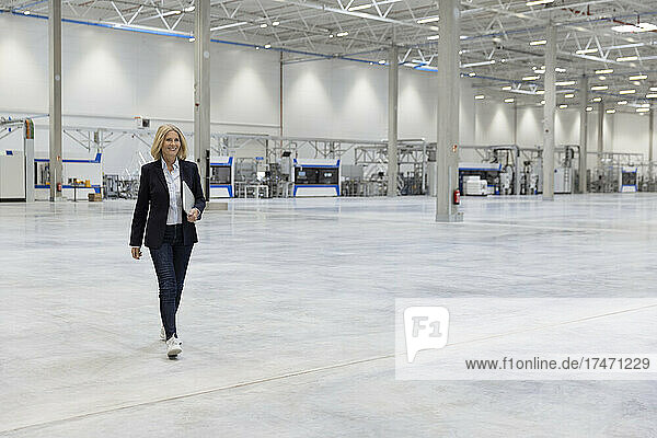 Businesswoman with laptop walking in industry